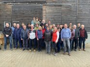 Personengruppe vor einer Holzwand