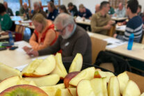 Aufgeschnittene Äpfel, dahinter Personen in einem Raum